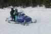 A young snowmobiler practices under her watchful parent's guidance