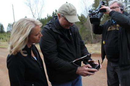 Tonia Tewell and Saw Brower look at drone footage while KARE11's Steve Eckert records the scene. Photo by Joe Friedrichs